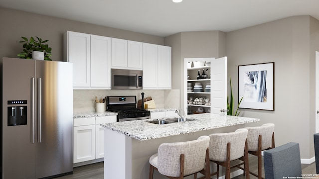 kitchen with an island with sink, dark wood-style floors, white cabinets, a sink, and stainless steel appliances