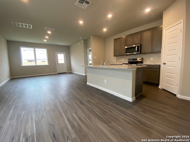 kitchen with baseboards, appliances with stainless steel finishes, visible vents, and dark wood-type flooring