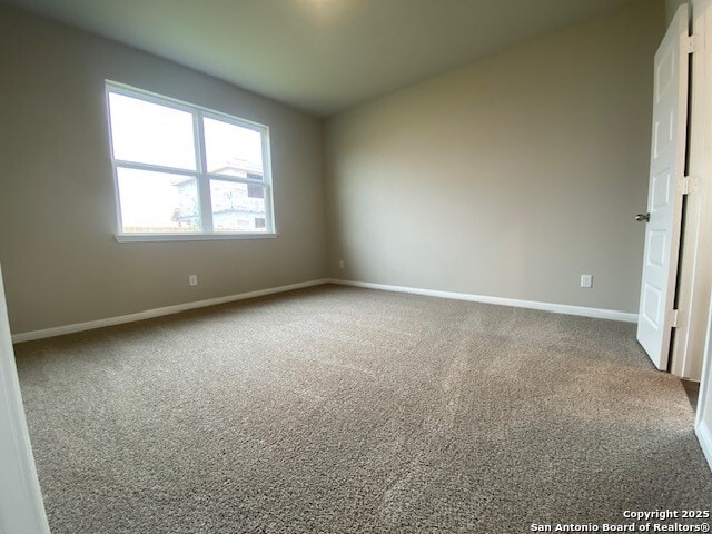 carpeted empty room with baseboards