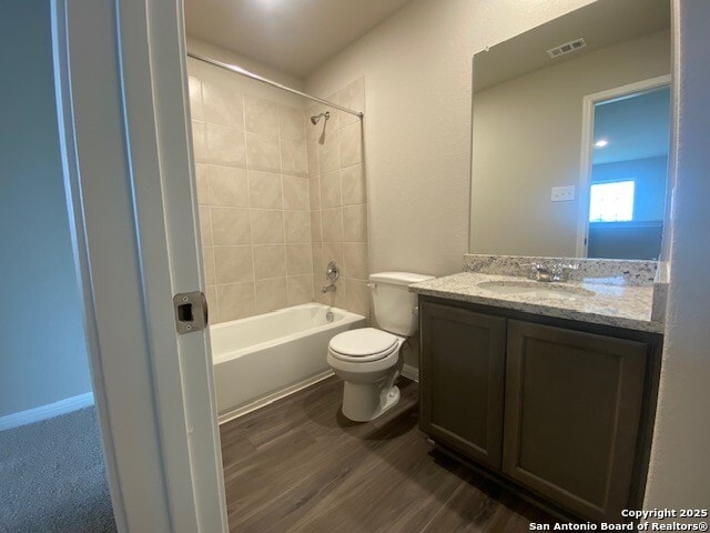 bathroom with visible vents, vanity, wood finished floors, toilet, and shower / bathing tub combination