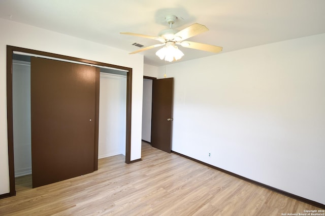 unfurnished bedroom featuring a ceiling fan, baseboards, light wood-type flooring, visible vents, and a closet
