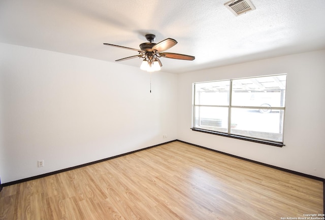 unfurnished room featuring a ceiling fan, a textured ceiling, visible vents, light wood-type flooring, and baseboards