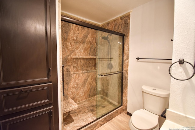 bathroom featuring wood finished floors, a stall shower, and toilet