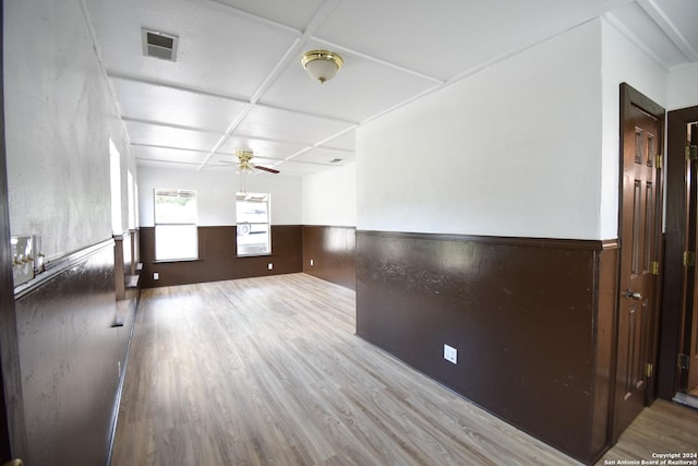 spare room featuring visible vents, wainscoting, wood finished floors, ceiling fan, and coffered ceiling