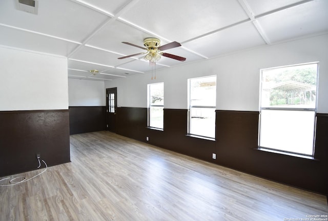 unfurnished room with a wainscoted wall, plenty of natural light, and coffered ceiling
