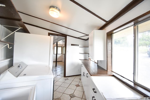 clothes washing area featuring washer and clothes dryer, cabinet space, and light tile patterned flooring