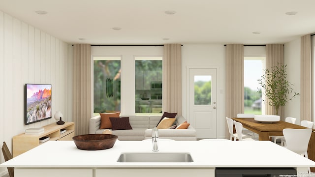 kitchen with dishwasher, light countertops, a sink, open floor plan, and an island with sink