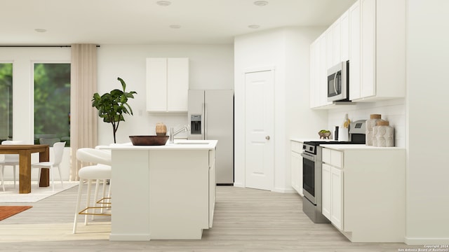 kitchen featuring a center island with sink, stainless steel appliances, a kitchen bar, and light wood-style flooring