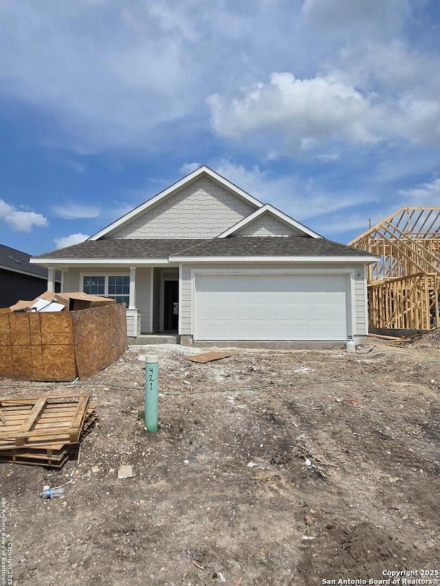 unfinished property with an attached garage and roof with shingles