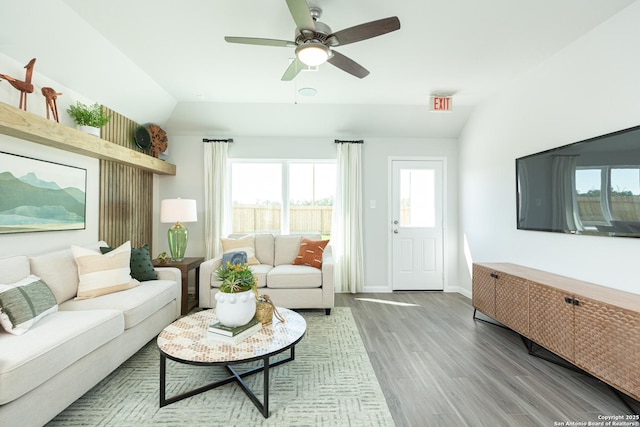 living area featuring a ceiling fan, lofted ceiling, wood finished floors, and a healthy amount of sunlight
