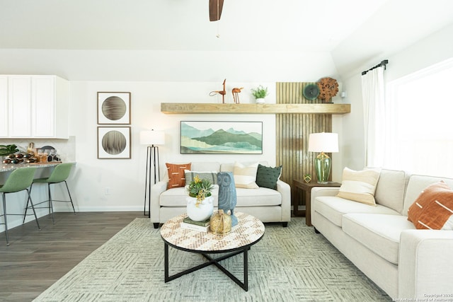 living room featuring baseboards, a ceiling fan, wood finished floors, and vaulted ceiling