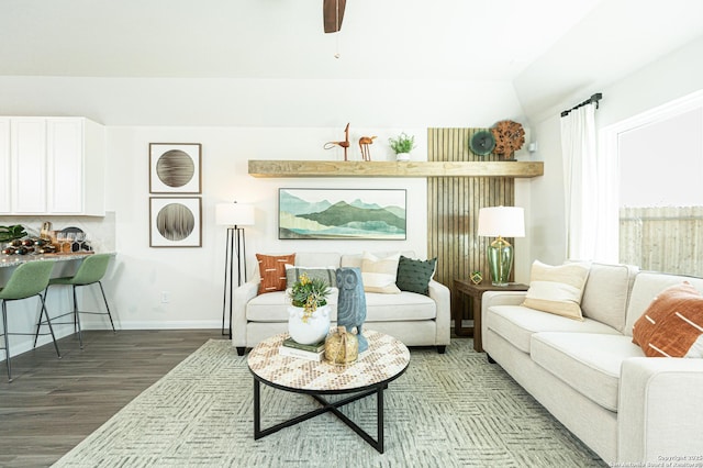 living area with baseboards, lofted ceiling, wood finished floors, and ceiling fan