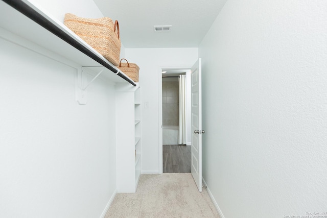 walk in closet featuring visible vents and light carpet
