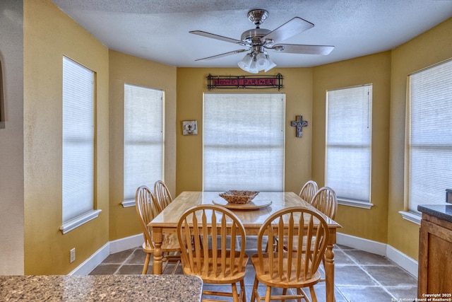dining area featuring tile patterned floors, ceiling fan, baseboards, and a textured ceiling
