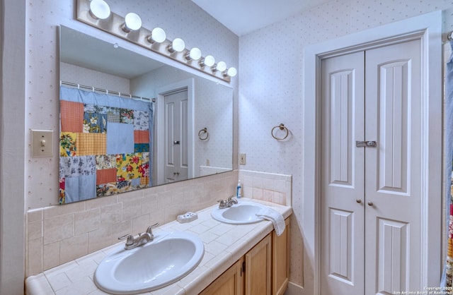 bathroom featuring a sink, a shower with curtain, wallpapered walls, and double vanity