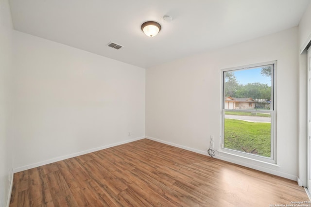 empty room featuring baseboards, visible vents, and wood finished floors
