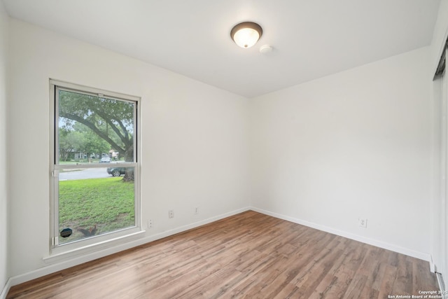 spare room featuring baseboards and wood finished floors