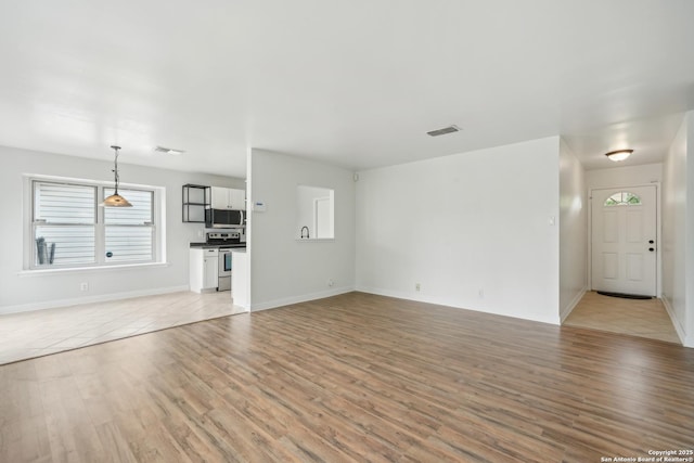 unfurnished living room featuring visible vents, light wood-style flooring, and a wealth of natural light
