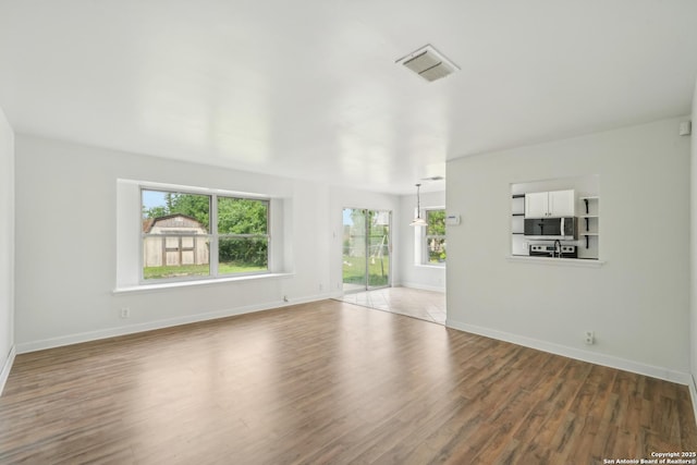 unfurnished living room with baseboards, wood finished floors, and visible vents