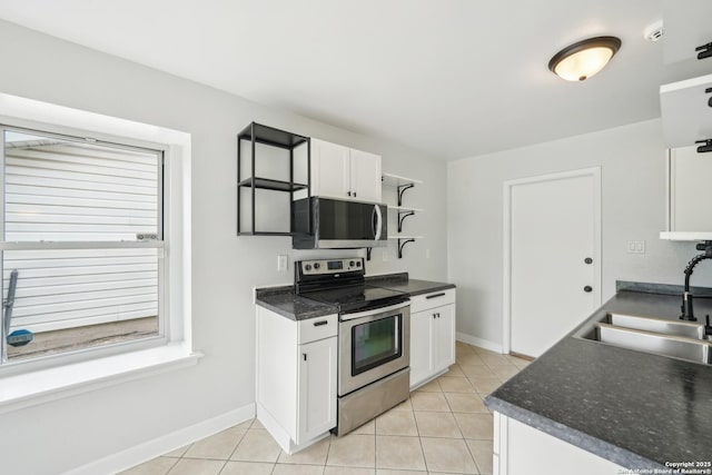 kitchen featuring a sink, stainless steel appliances, baseboards, white cabinetry, and light tile patterned floors