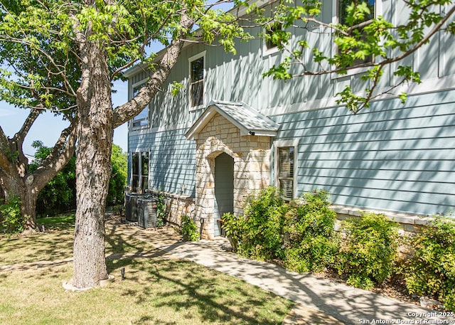 view of exterior entry featuring a yard and stone siding