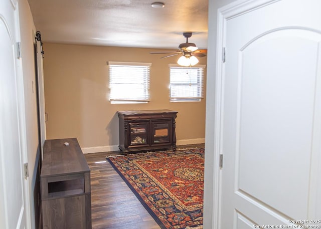 hall with baseboards, a barn door, and dark wood finished floors
