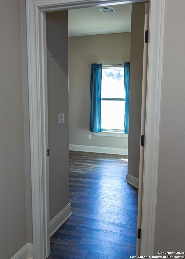 hallway featuring baseboards, visible vents, and wood finished floors