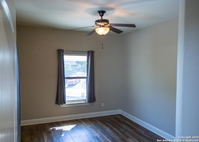 empty room with baseboards, ceiling fan, and dark wood finished floors