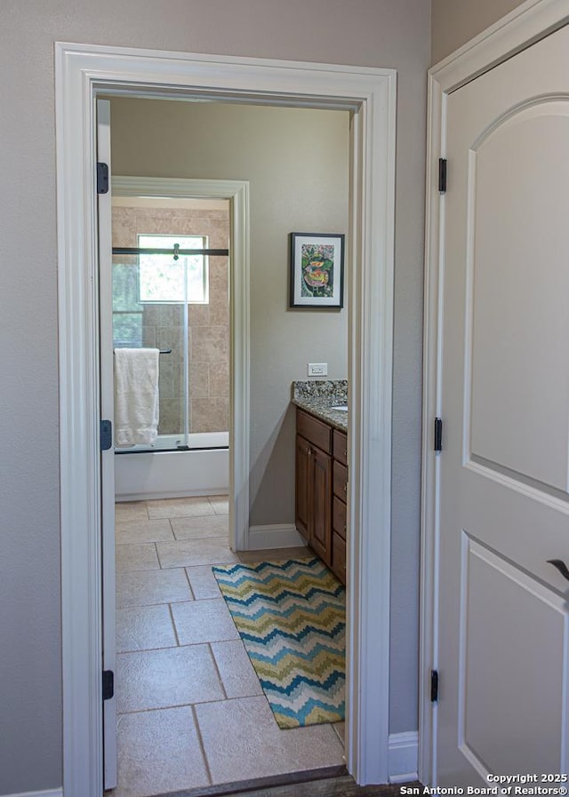 full bathroom with baseboards, shower / bath combination with glass door, and vanity