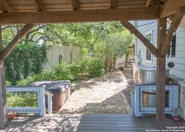 wooden terrace featuring a hot tub and a fenced backyard