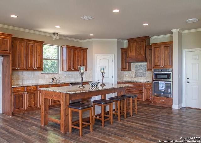 kitchen featuring a kitchen island, visible vents, a sink, and dark wood finished floors