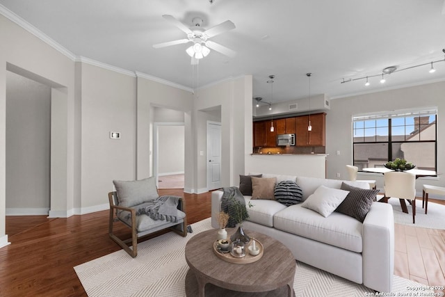 living room with baseboards, ornamental molding, a ceiling fan, and wood finished floors