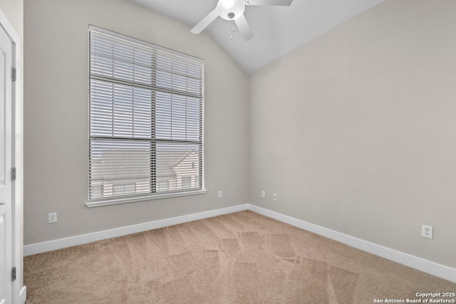 empty room with light colored carpet, a ceiling fan, baseboards, and vaulted ceiling
