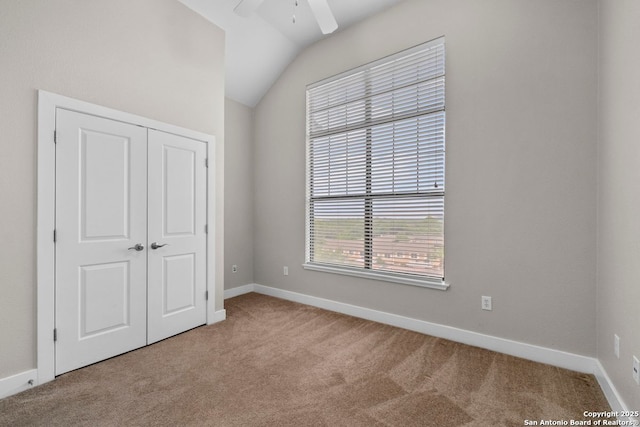 unfurnished bedroom with carpet, a ceiling fan, baseboards, vaulted ceiling, and a closet