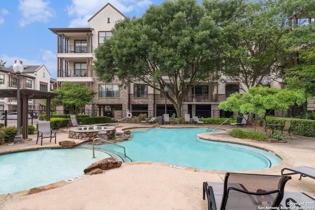 community pool featuring a hot tub, a patio area, and fence