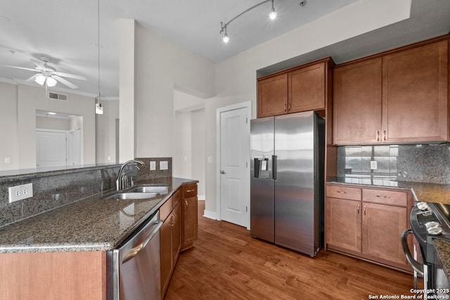 kitchen with a sink, appliances with stainless steel finishes, decorative backsplash, and dark stone counters