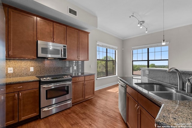 kitchen featuring appliances with stainless steel finishes, a sink, light wood-style flooring, visible vents, and ornamental molding