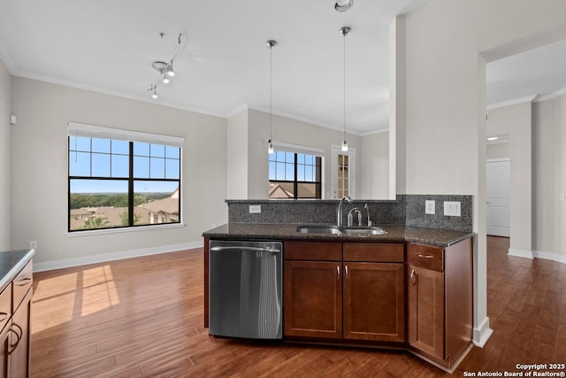 kitchen with stainless steel dishwasher, wood finished floors, a sink, and tasteful backsplash