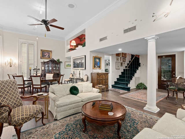 living area with ornate columns, ceiling fan, visible vents, and wood finished floors
