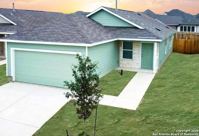 view of front of house featuring a garage, fence, driveway, roof with shingles, and a yard