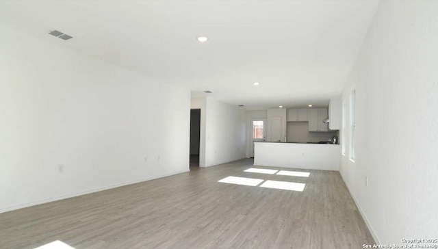 unfurnished living room with visible vents, recessed lighting, light wood finished floors, and baseboards