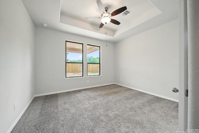 unfurnished room featuring ceiling fan, visible vents, baseboards, a tray ceiling, and carpet flooring