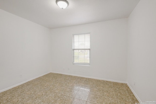 empty room featuring light tile patterned floors and baseboards