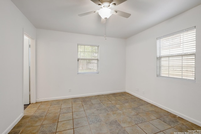 spare room with baseboards, a ceiling fan, and stone finish floor