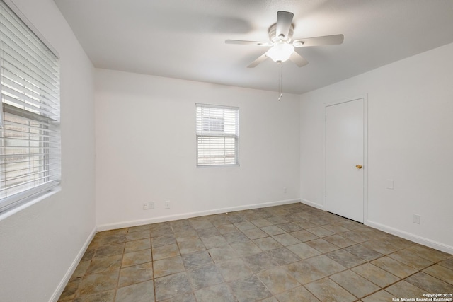 unfurnished room with a ceiling fan and baseboards