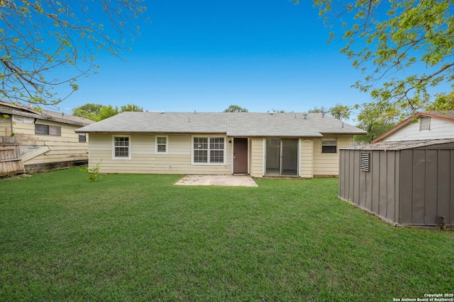rear view of property with fence, a storage shed, an outbuilding, a lawn, and a patio