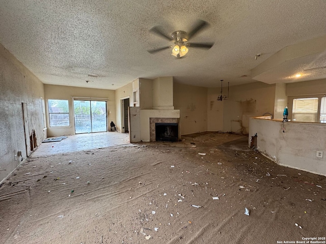unfurnished living room featuring a ceiling fan, a textured ceiling, and a fireplace