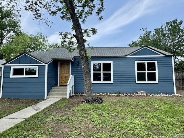 single story home with roof with shingles, board and batten siding, and a front yard