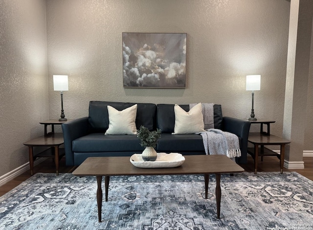 living room featuring baseboards, a textured wall, and wood finished floors
