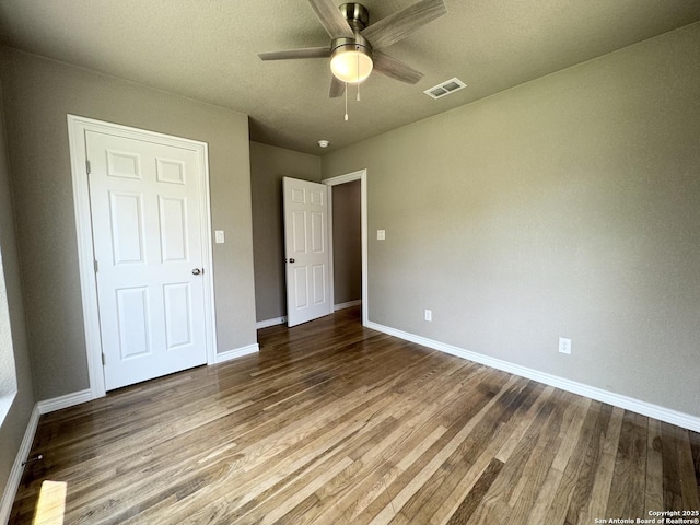 unfurnished bedroom with baseboards, ceiling fan, wood finished floors, and visible vents